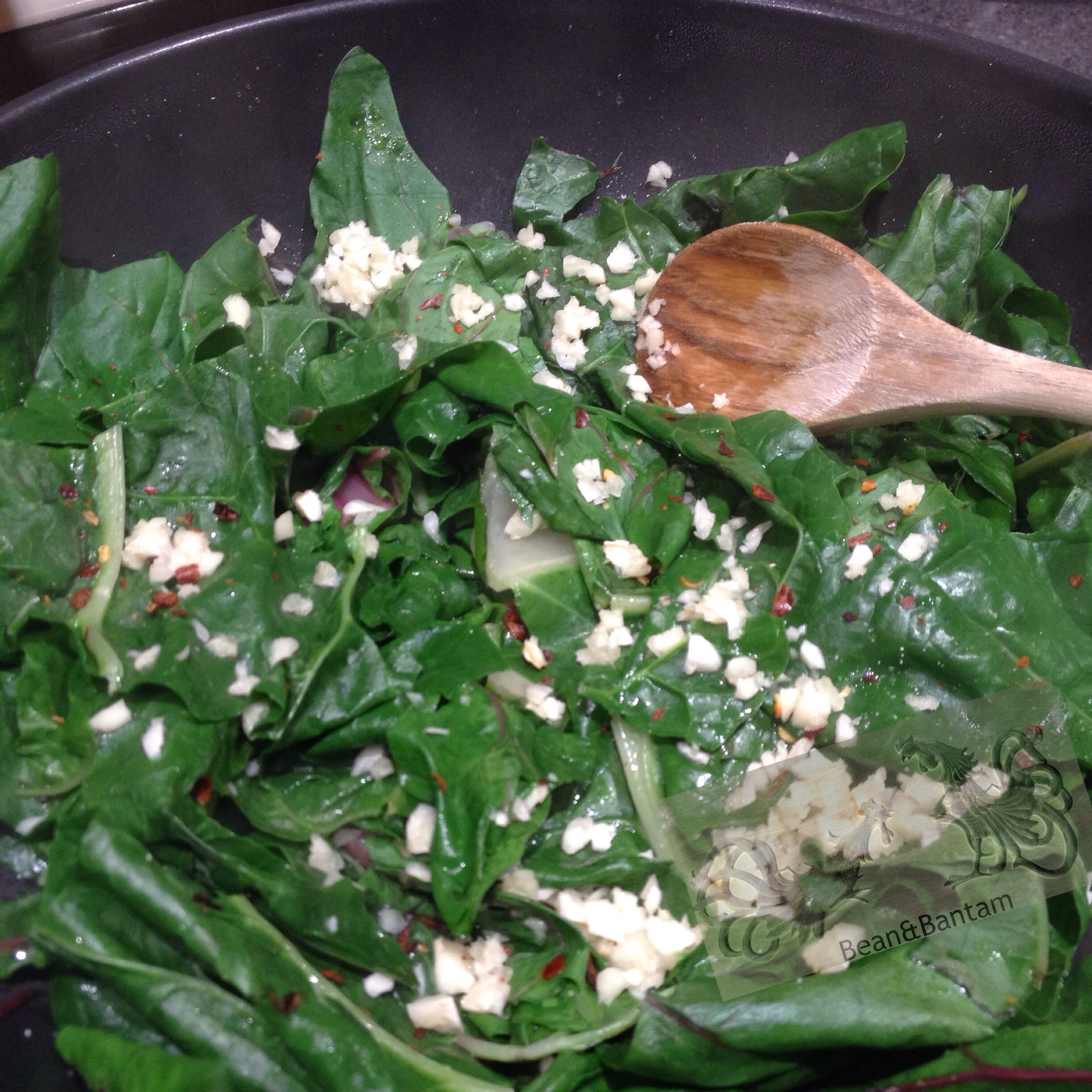 Adding in the garlic and the red pepper flakes. to the wilted chard 